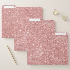 three pink glittered file folders next to a pair of scissors