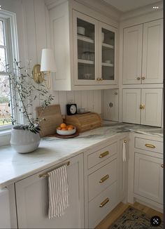 a kitchen with white cabinets and gold handles