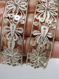 two silver bracelets with intricate designs on them