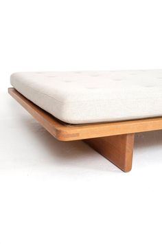 a wooden bench with a white cushion on the top and bottom part of it's legs