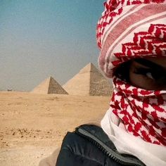 a person wearing a red and white scarf with pyramids in the background