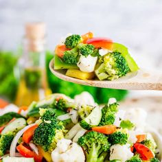 broccoli, cauliflower, carrots and cucumber stir fry on a wooden spoon