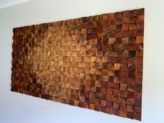 a wooden wall hanging on the side of a white wall with wood squares in it