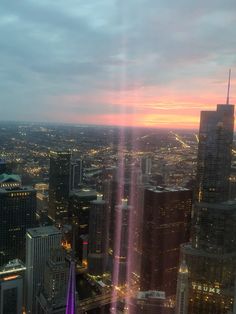 the sun is setting over a city with tall buildings and skyscrapers in the foreground