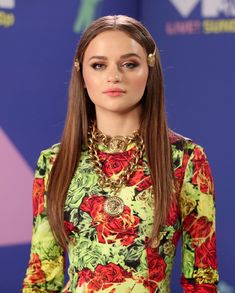 a woman with long hair wearing a colorful dress and gold jewelry on the red carpet