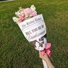 a person holding up a paper hat with flowers on it and the words, will you be my bridesmaid?