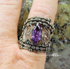 a woman's hand holding a ring with an amethorate stone