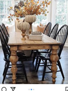 a dining room table with chairs and a vase filled with flowers on top of it