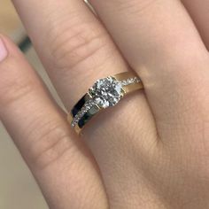 a woman's hand with a diamond and gold ring on top of her finger