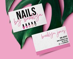 two business cards sitting on top of a green leaf next to a pink and white background