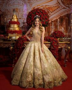 a woman standing in front of a table wearing a gold dress with flowers on it