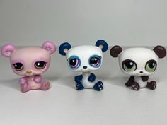 three little toy animals sitting next to each other on a white surface with one animal looking at the camera