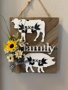 a wooden sign that says family with a cow and flowers hanging from the side of it