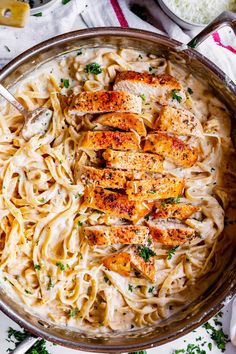 chicken alfredo in a skillet with parmesan cheese and parsley on the side