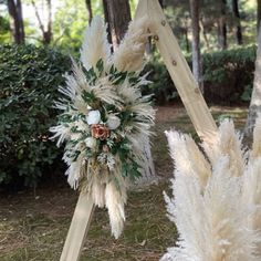 some white flowers and feathers are on display in front of a wooden stand with two poles