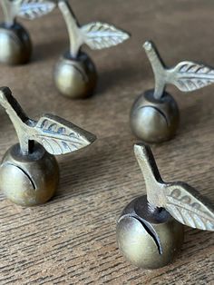 four metal cherries with leaves on them sitting on a wooden table next to each other