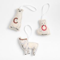 three ornaments are shown on a white surface, one has a dog ornament and the other is a sheep