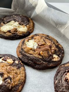 four chocolate cookies with white cream on top are sitting in a baking pan, ready to be eaten