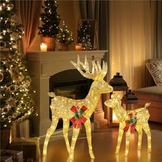 two lighted deer standing next to each other in front of a christmas tree and fireplace