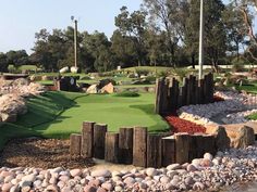 an artificial golf course surrounded by rocks and trees