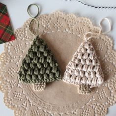 two crocheted ornaments sitting on top of a doily next to a piece of string