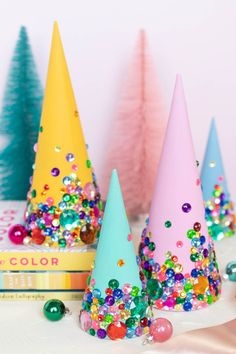 three colorful party hats sitting on top of a table next to christmas decorations and books