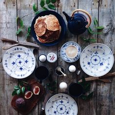 a table topped with blue and white plates covered in food next to utensils