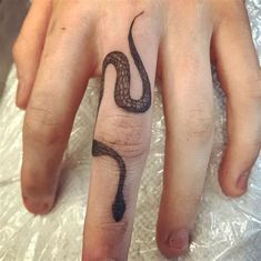 a person's hand with a snake tattoo on it