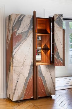 a cabinet with marble and wooden doors in a living room next to a hardwood floor