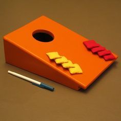 an orange and red object sitting on top of a table next to a pencil holder