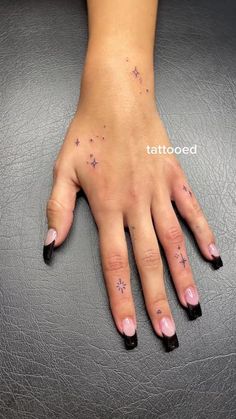 a woman's hand with stars on it and the word tattooed in white ink