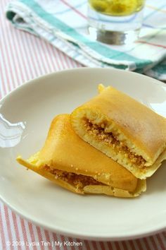 two pieces of food on a white plate with a red and white table cloth in the background