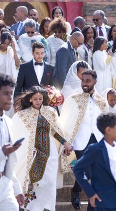 a group of people dressed in white are walking down the steps together and one person is holding his hand out