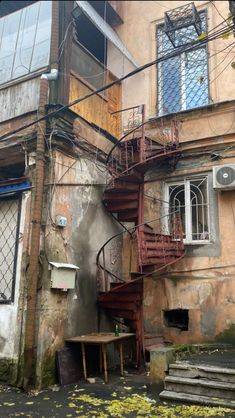 a car parked in front of an old building with a fire escape on the second floor