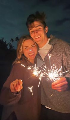 a man and woman holding sparklers in front of their faces with the lights on