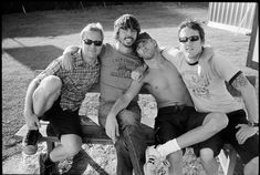 black and white photograph of three men sitting on a park bench with their arms around each other