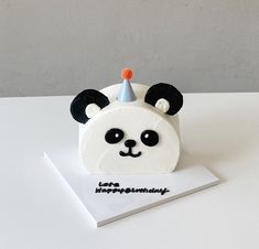 a birthday cake with a panda bear wearing a party hat on it's head