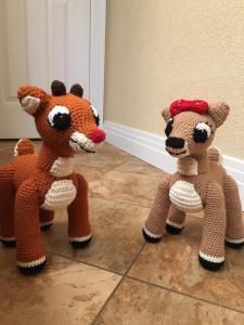 two crocheted stuffed animals sitting on the floor next to each other in front of a door