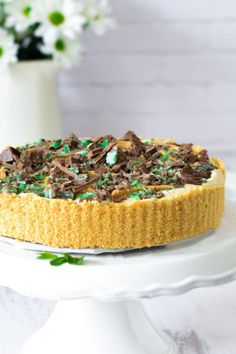 a chocolate peppermint tart on a white plate with flowers in the background