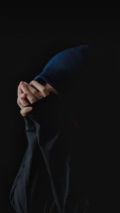 a person with their hands on the back of his hoodie, in front of a black background