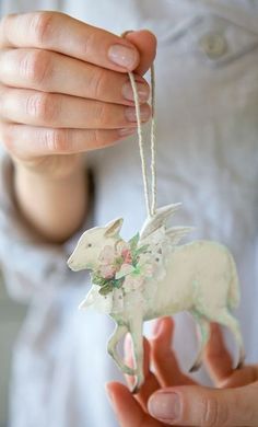 a person holding a white ornament with a horse on it's back