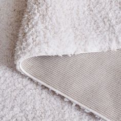 a close up of a white rug on the floor with a gray and white blanket