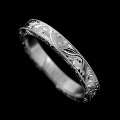 a wedding ring with intricate designs on it's side, against a black background