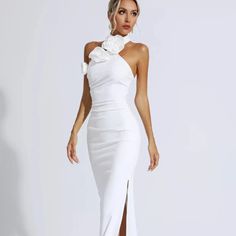 a woman wearing a white dress with one shoulder and high slited skirt, standing in front of a white background