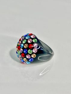 This glamorous ring is handcrafted on a black acrylic dome shaped setting, while embellished with multicolored mixed Swarovski crystal stones. The ring is lightweight, comfortable to wear, and is perfect for styling up with any look. The care and craftsmanship that went into creating this ring truly showcases itself as art at your fingertips. The ring sparkles even more beautifully in person and you will get endless complements when wearing this ring. Arrives beautifully packaged in a luxury gif Multicolor Crystal Rings For Gift, Party Crystal Ring With Rhinestones, Rainbow Ring For Party Jewelry, Rainbow Ring For Parties, Multicolor Party Ring Jewelry, Rainbow Party Ring Jewelry, Multicolor Crystal Rings For Party, Unique Multicolor Rings For Party, Multicolor Multi-stone Crystal Ring Gift