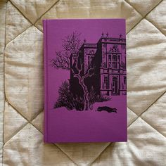 a purple book sitting on top of a bed