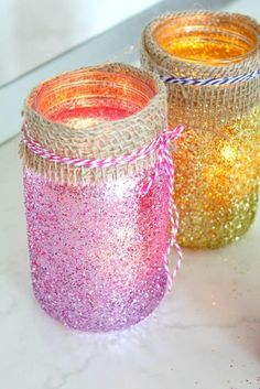 three jars with glitter on them sitting on a table