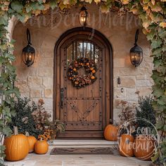 a wooden door surrounded by pumpkins and greenery in front of a stone building