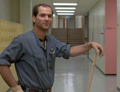 a man holding a broom in an empty hallway