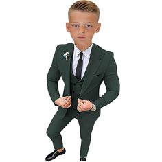 a young boy in a green suit and tie posing for the camera with his hands on his hips